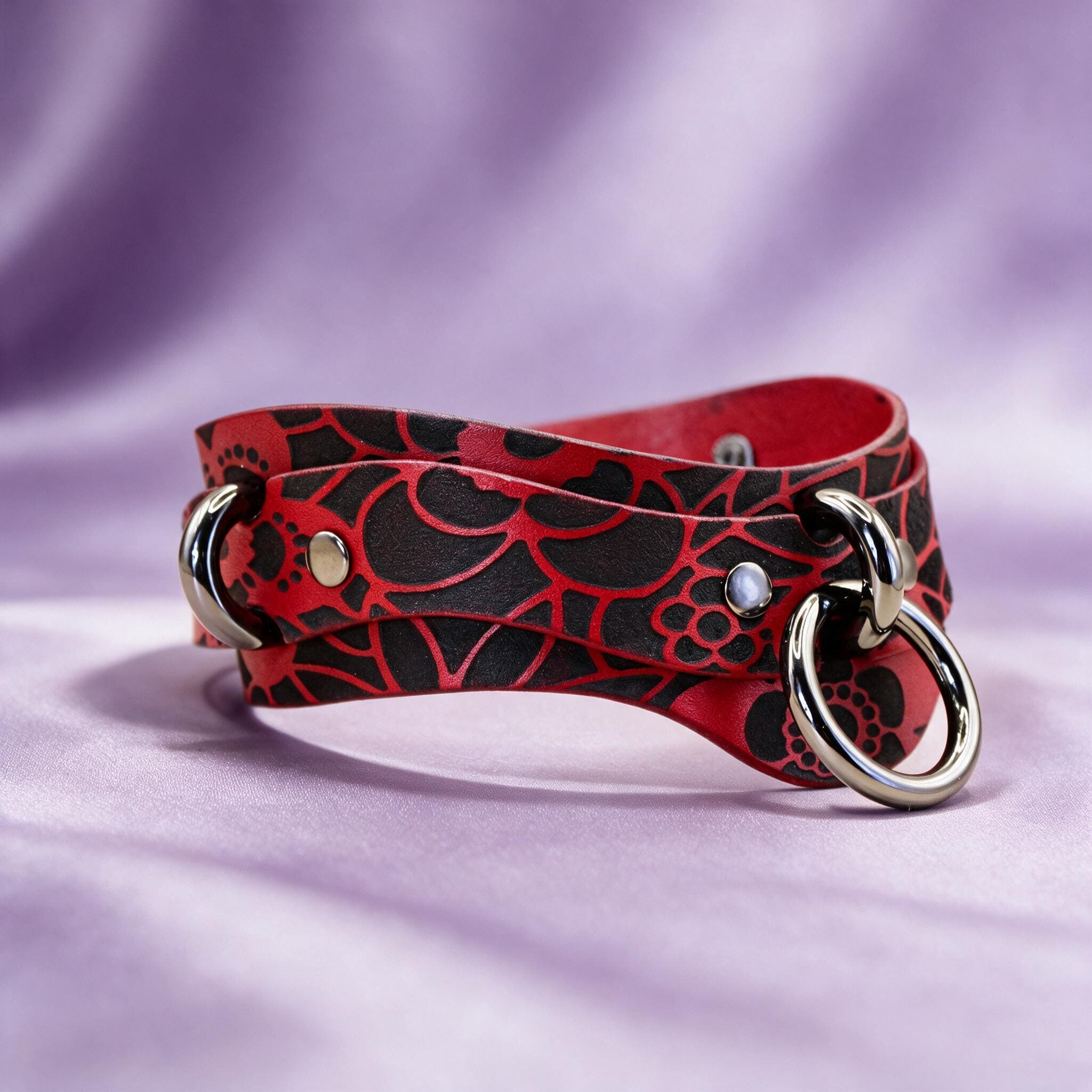 A red and black leather choker necklace with a silver metal ring and a silver metal clasp.