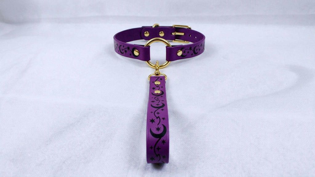 A purple collar with a gold buckle and a black star-and-crescent design on the strap is displayed against a white background.