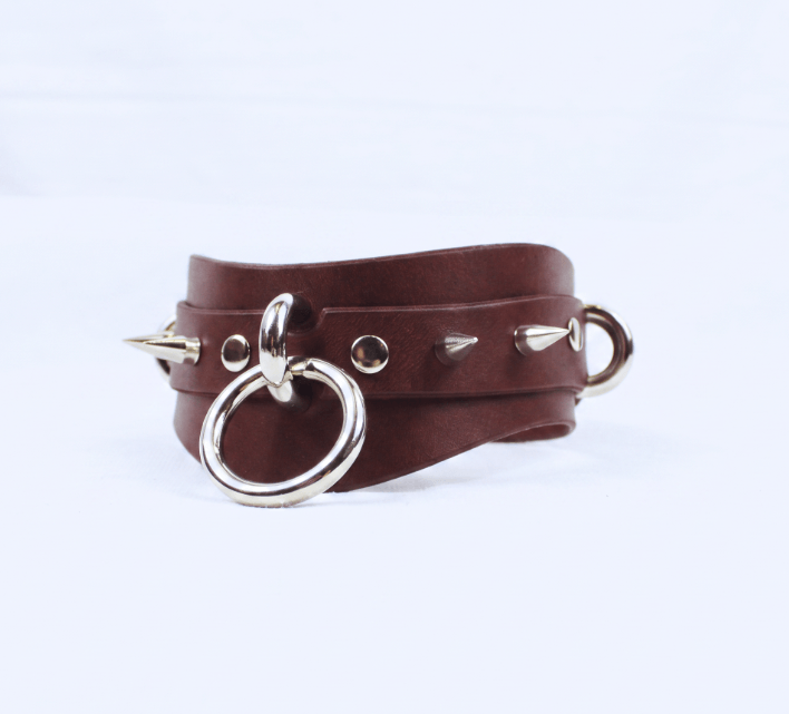 A brown leather choker necklace with metal spikes protruding from it.