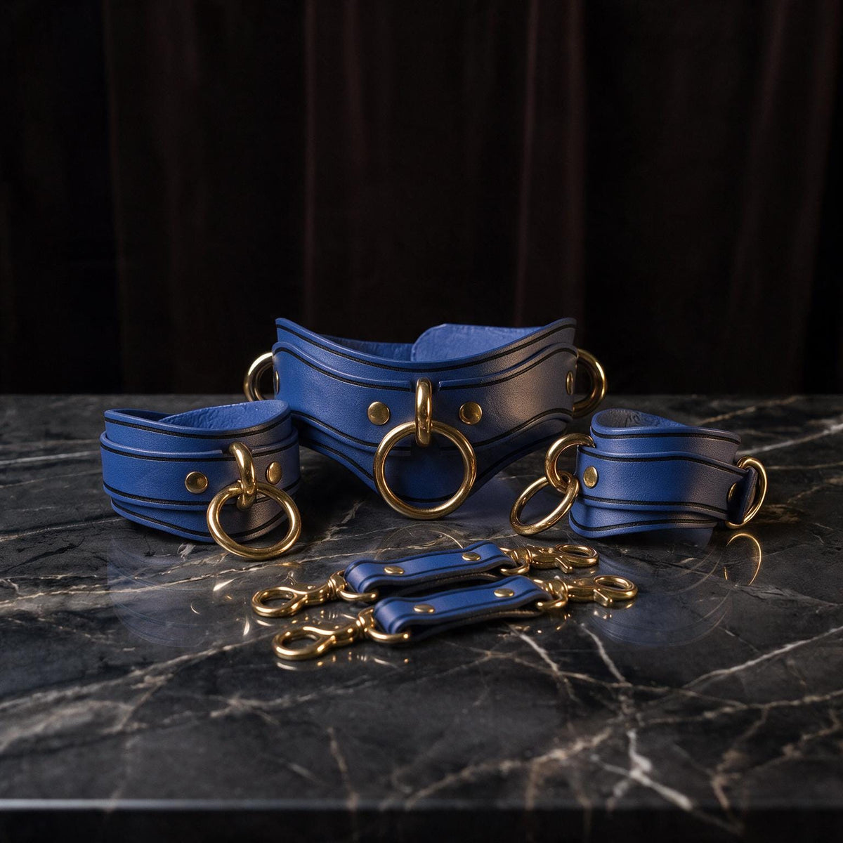 A set of blue leather choker necklaces with gold-colored metal rings, arranged on a marble surface.