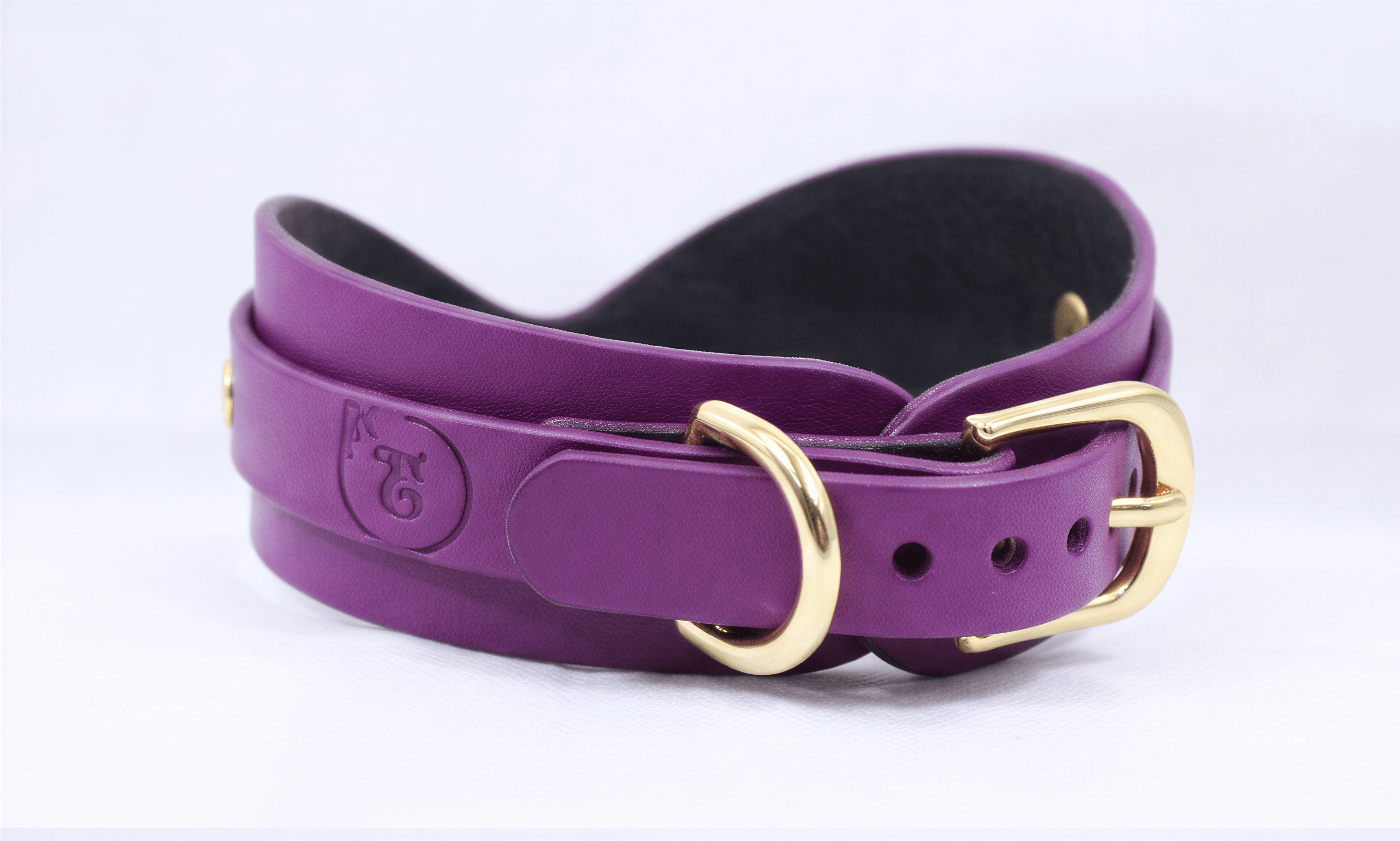 A purple leather belt with a gold buckle, featuring a logo on the buckle.