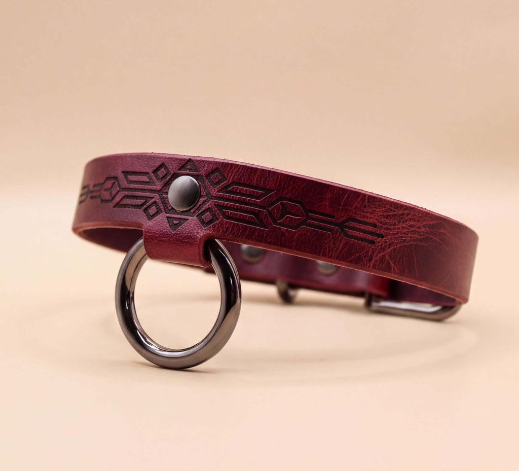 A burgundy leather dog collar with a metal ring and a geometric pattern design.