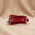 A red leather choker necklace with a metal ring and decorative elements on the clasp.