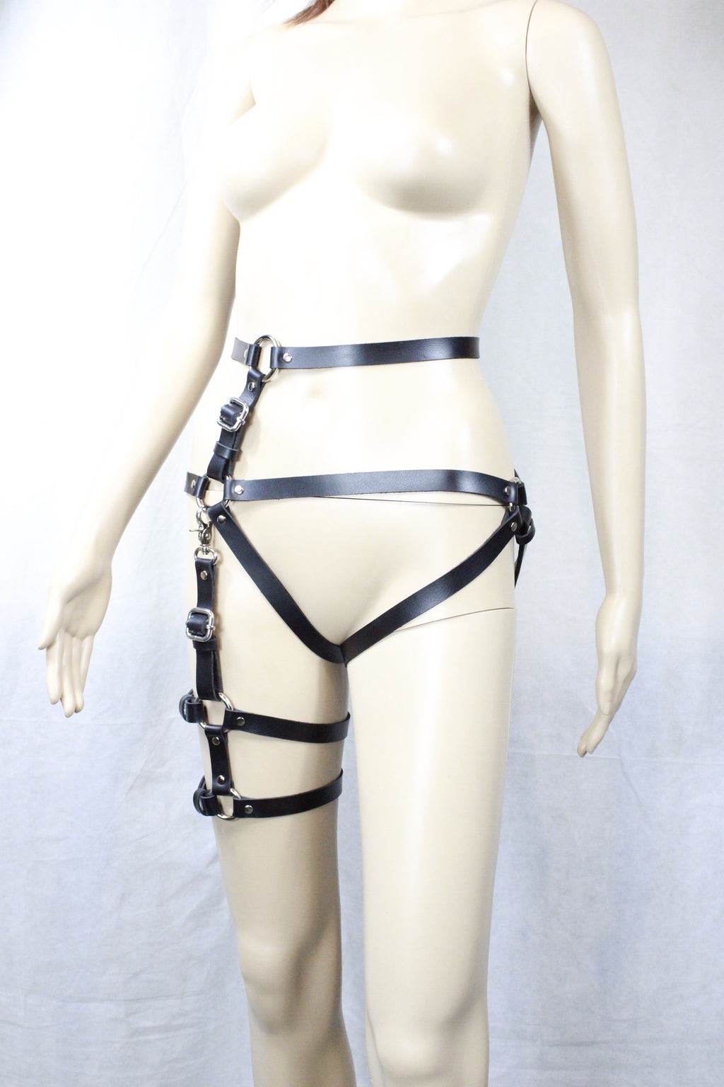 A mannequin wearing a black leather strap with multiple buckles and straps, creating a striking and edgy appearance.