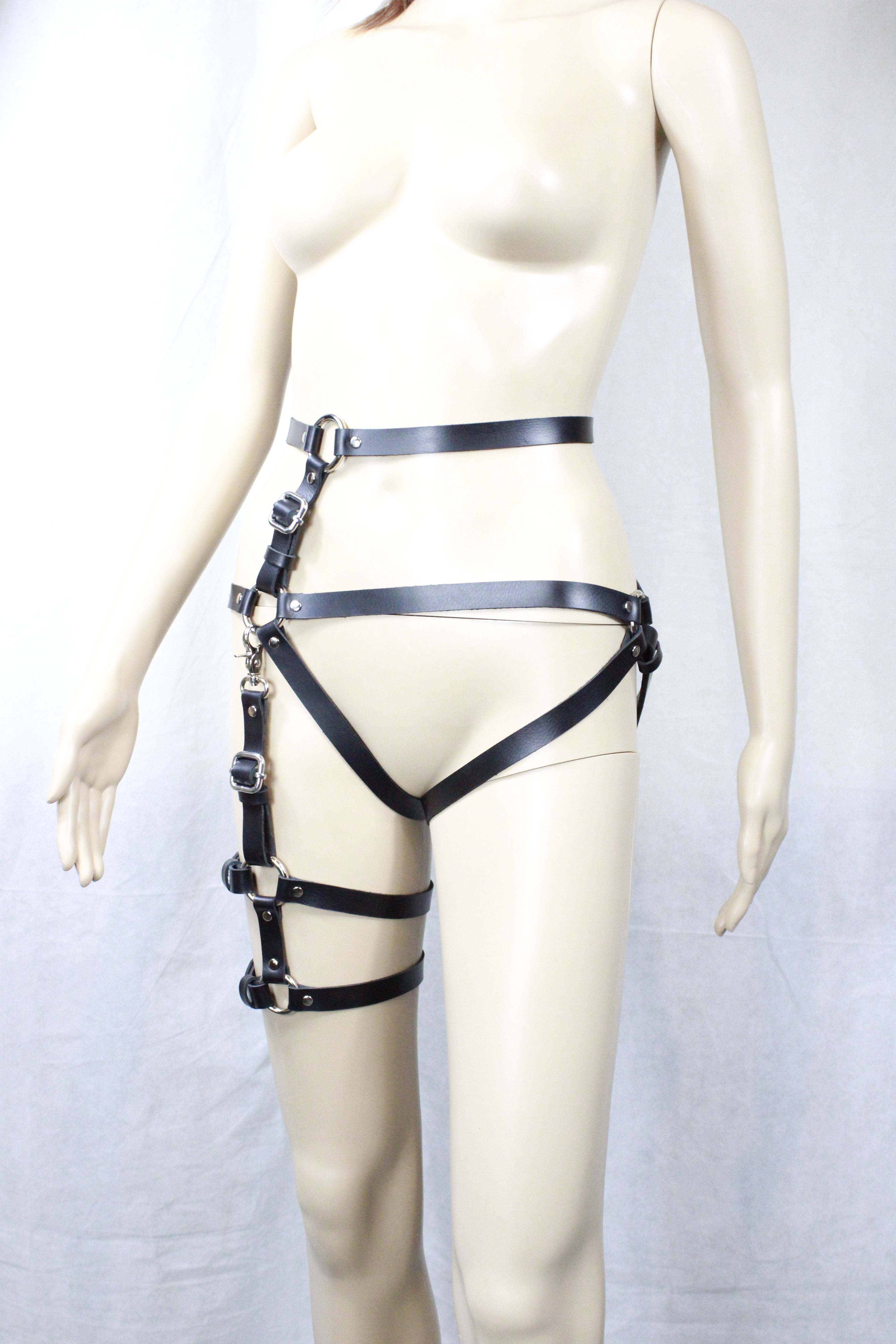 A mannequin wearing a black leather strap with multiple buckles and straps, creating a striking and edgy appearance.