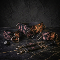 a collection of leather straps and charms with intricate designs, including floral patterns and celestial motifs, arranged on a dark surface.