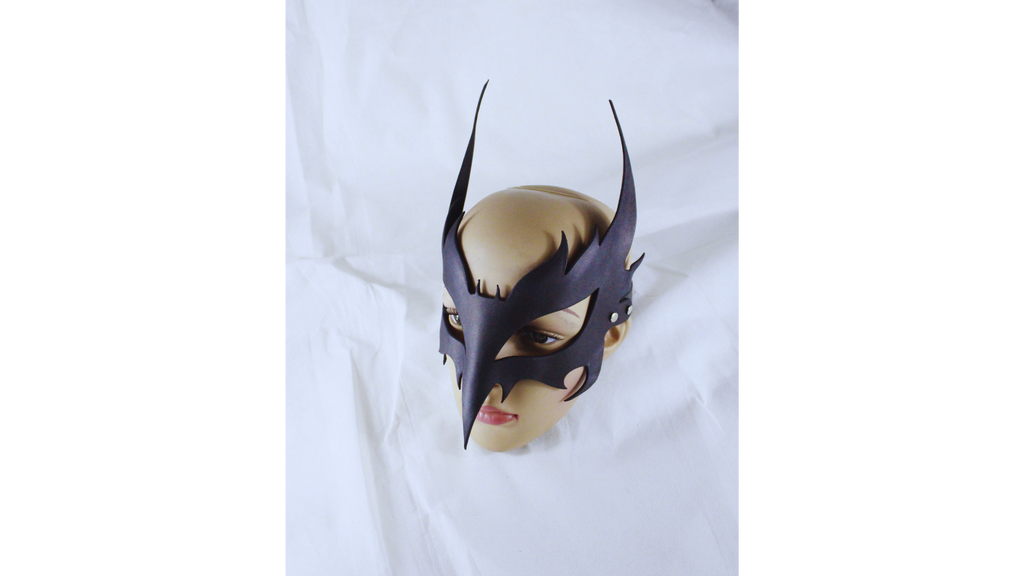 A mannequin head wearing a black mask with sharp, pointed features is displayed against a white background.