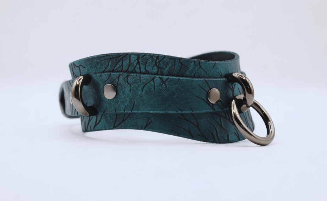 A dark green leather choker necklace with metal rings and a metal clasp.