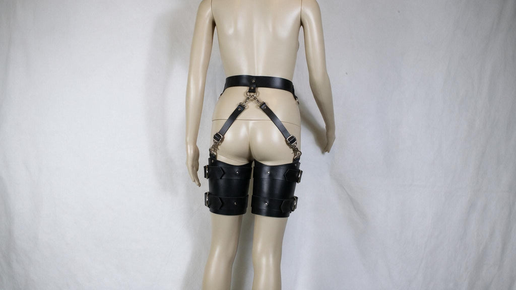A mannequin wearing black leather straps with buckles, which appear to be designed for use as a waist belt or garter belt.