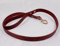 A red leather dog leash with a heart-shaped metal clasp and a gold-colored metal buckle.