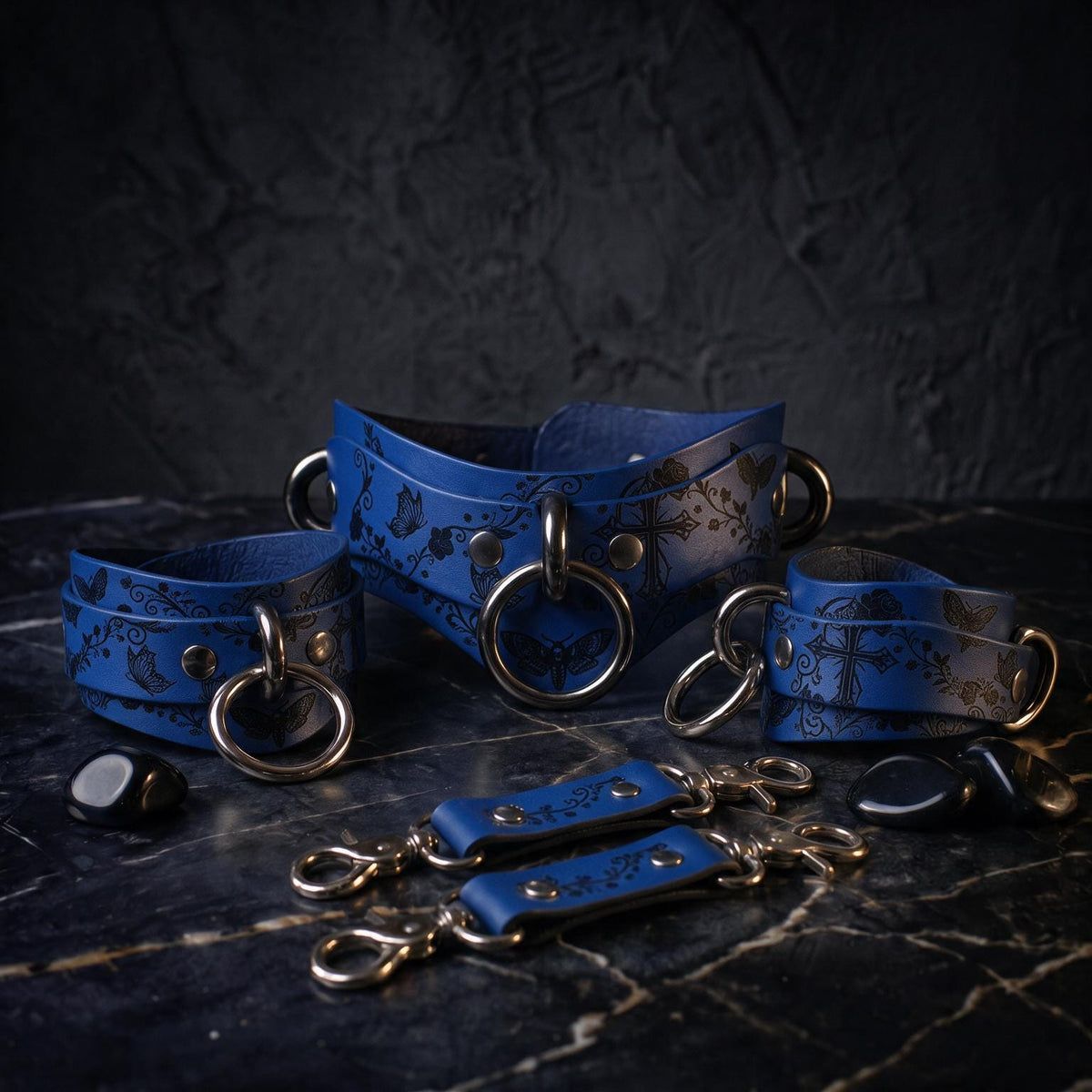 A set of blue leather straps with metal rings and buckles, arranged on a dark surface.
