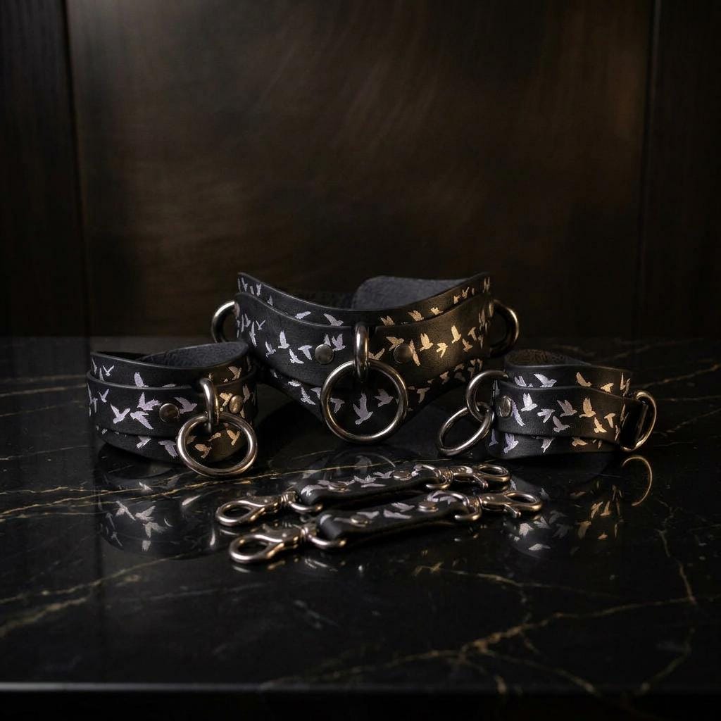 a set of black leather straps with white bird designs, arranged on a black marble surface.