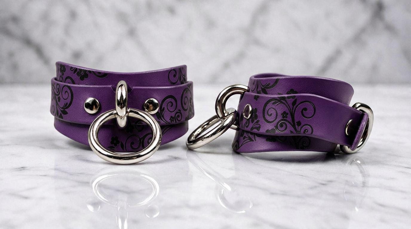 a pair of purple leather straps with metal rings and buckles, placed on a marble surface.