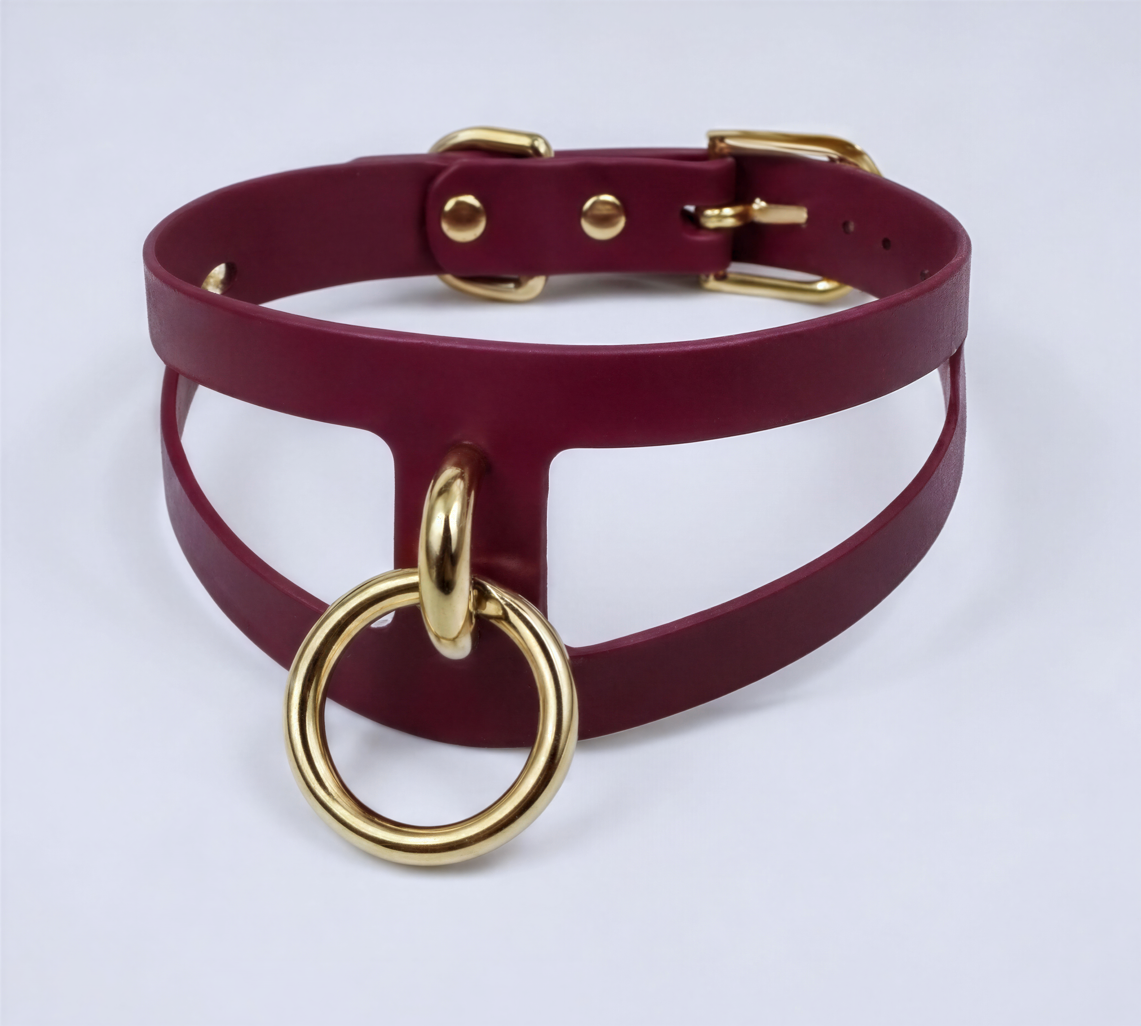 A burgundy leather choker necklace with a gold ring and buckle.