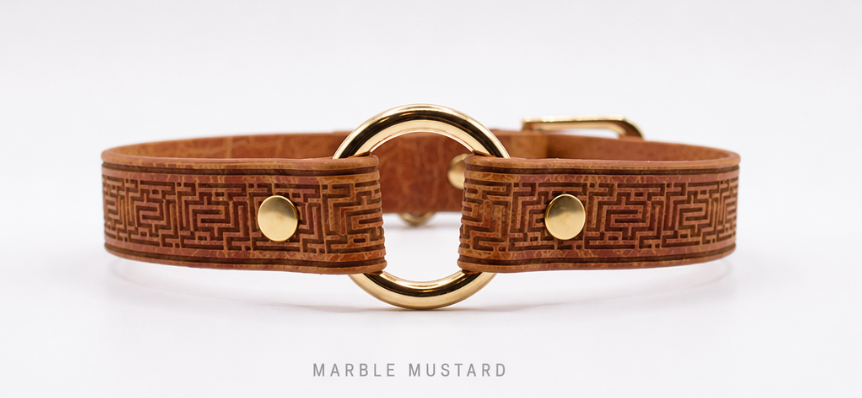 A brown leather collar with a gold metal buckle and a marble mustard pattern.
