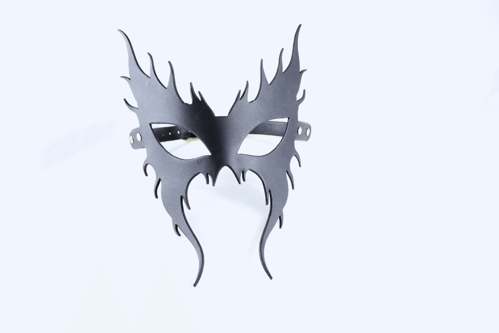 A black mask with a stylized design, resembling a flame or fire-like shape, is shown against a white background.