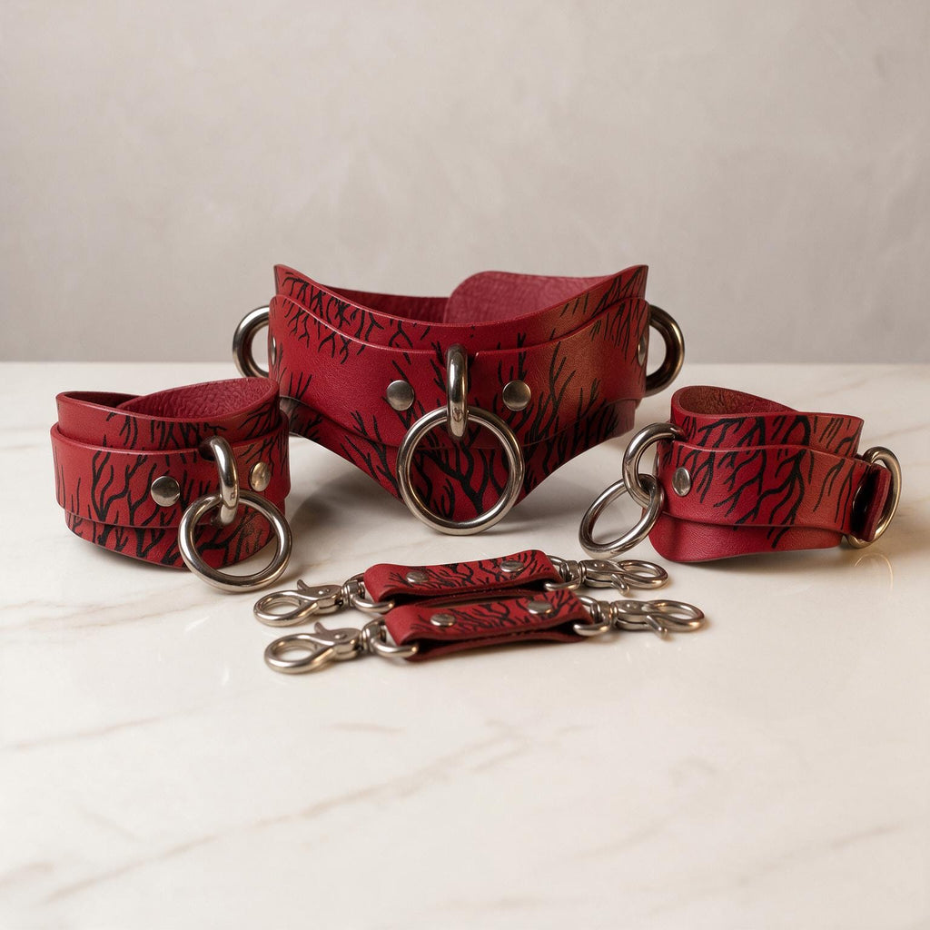 A set of red leather straps with metal rings and buckles, arranged on a white surface.