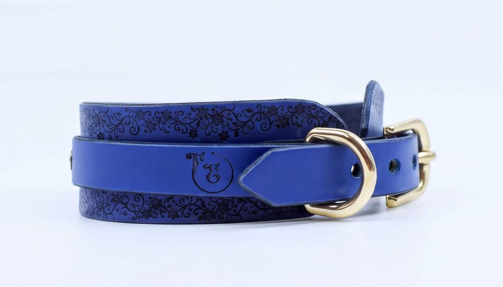 A blue leather belt with a gold buckle, featuring a decorative pattern on the surface.