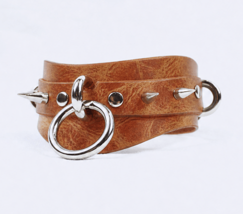 A brown leather choker necklace with metal spikes protruding from it.