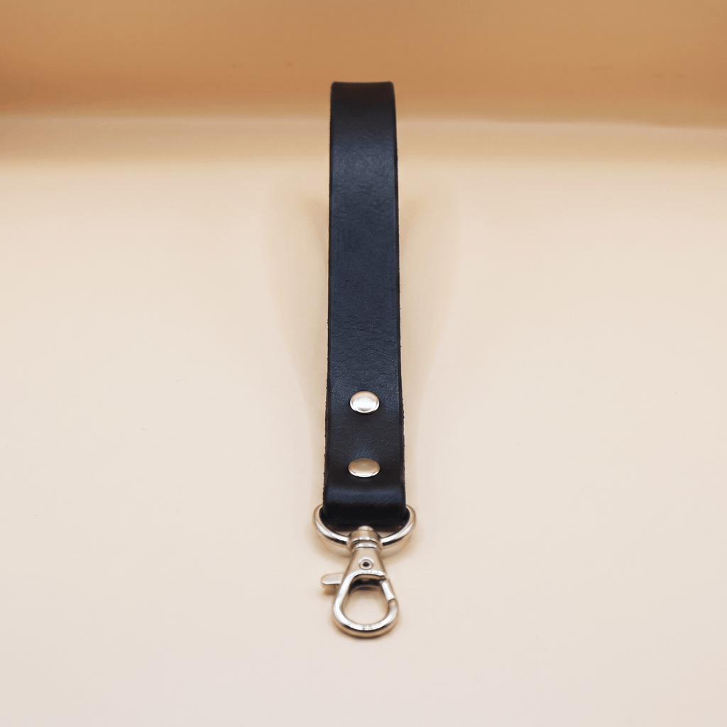 A black leather strap with a metal clasp and hook attached to it.