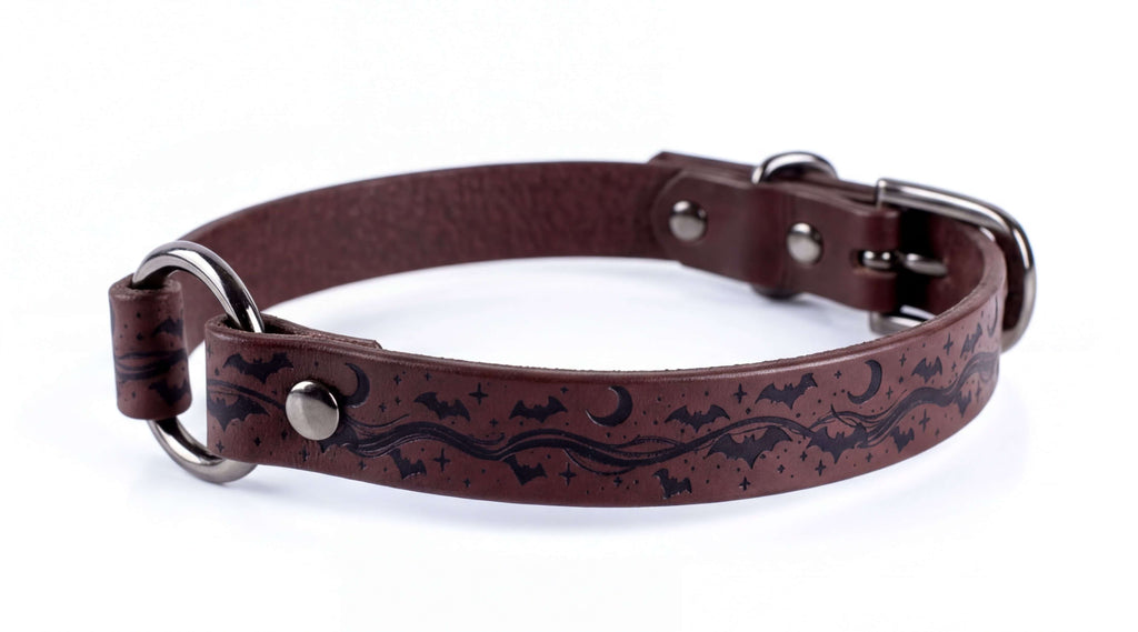 A brown leather dog collar with a night sky and bats design.
