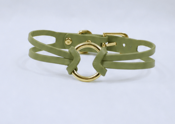 A green leather choker necklace with a gold-colored circular clasp.
