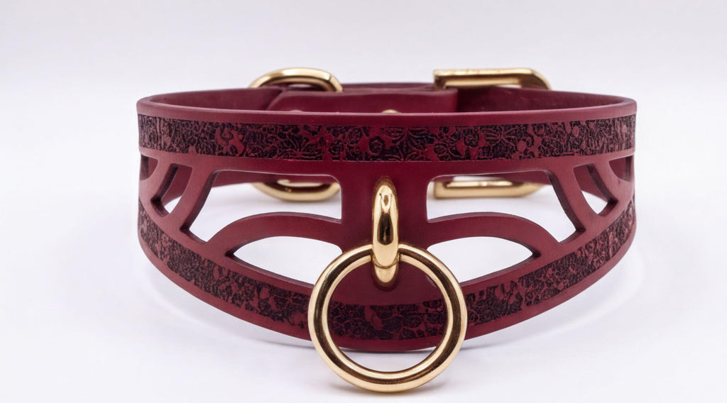 A burgundy leather choker collar with a gold-colored metal ring and buckle.