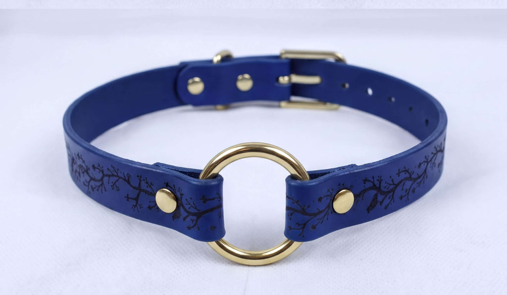A blue leather choker necklace with a gold-colored metal ring and a gold-colored metal buckle.