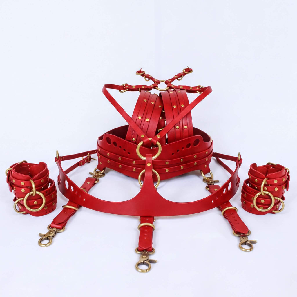 A set of red leather restraints or restraints with gold-colored metal studs, arranged on a white background.