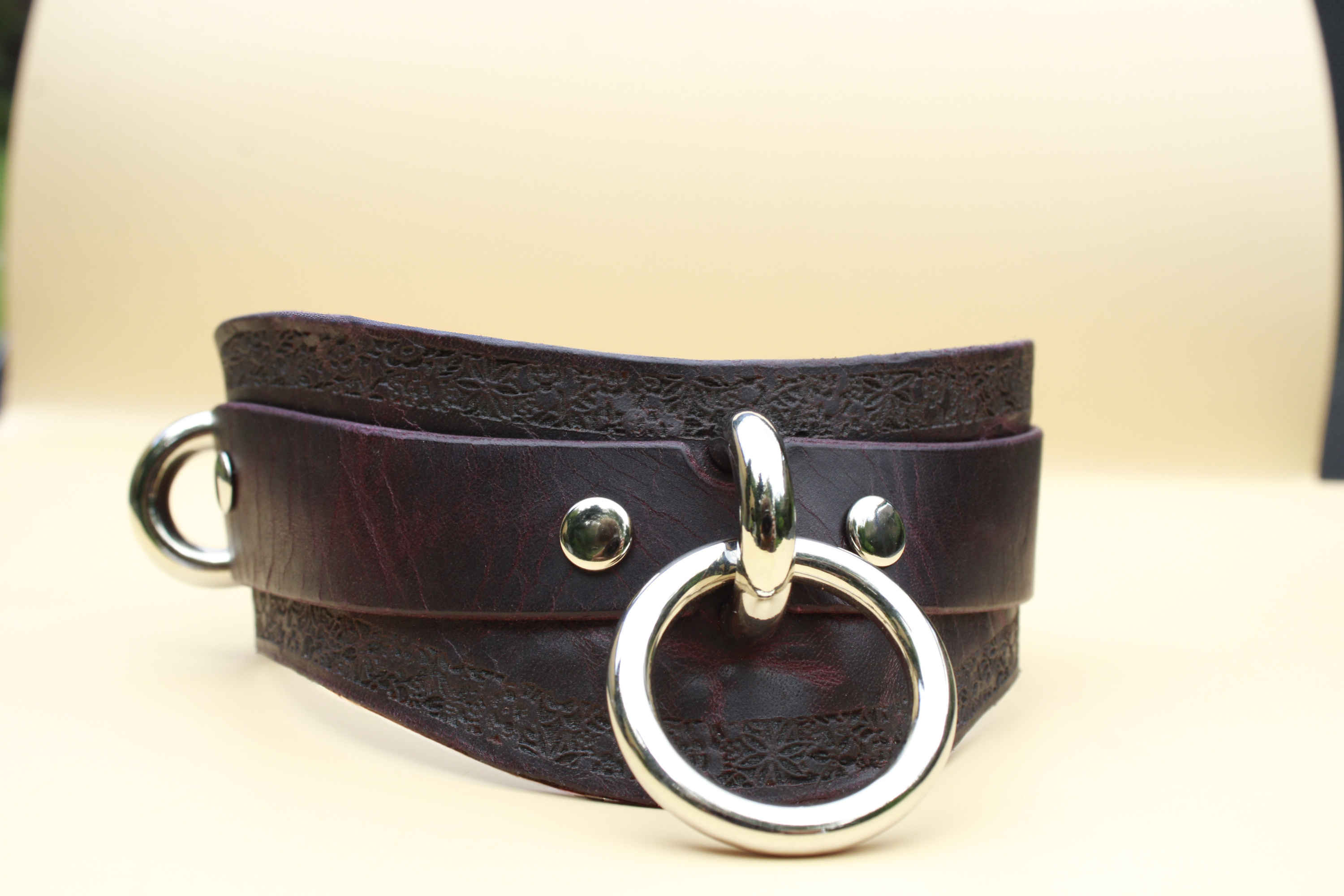 A dark brown leather corset with metal rings and a metal buckle.