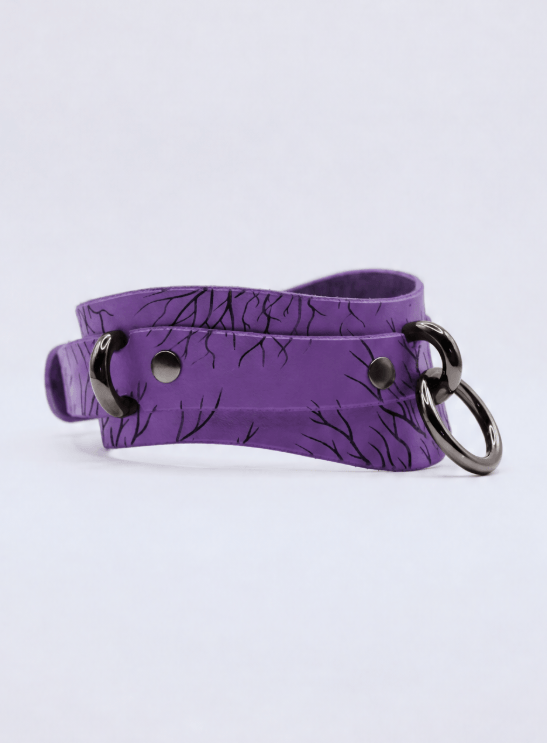 A purple choker necklace with a black tree-like pattern and two metal rings.