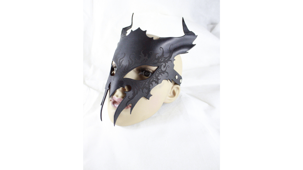 A black mask with a skull-like design is shown against a white background.