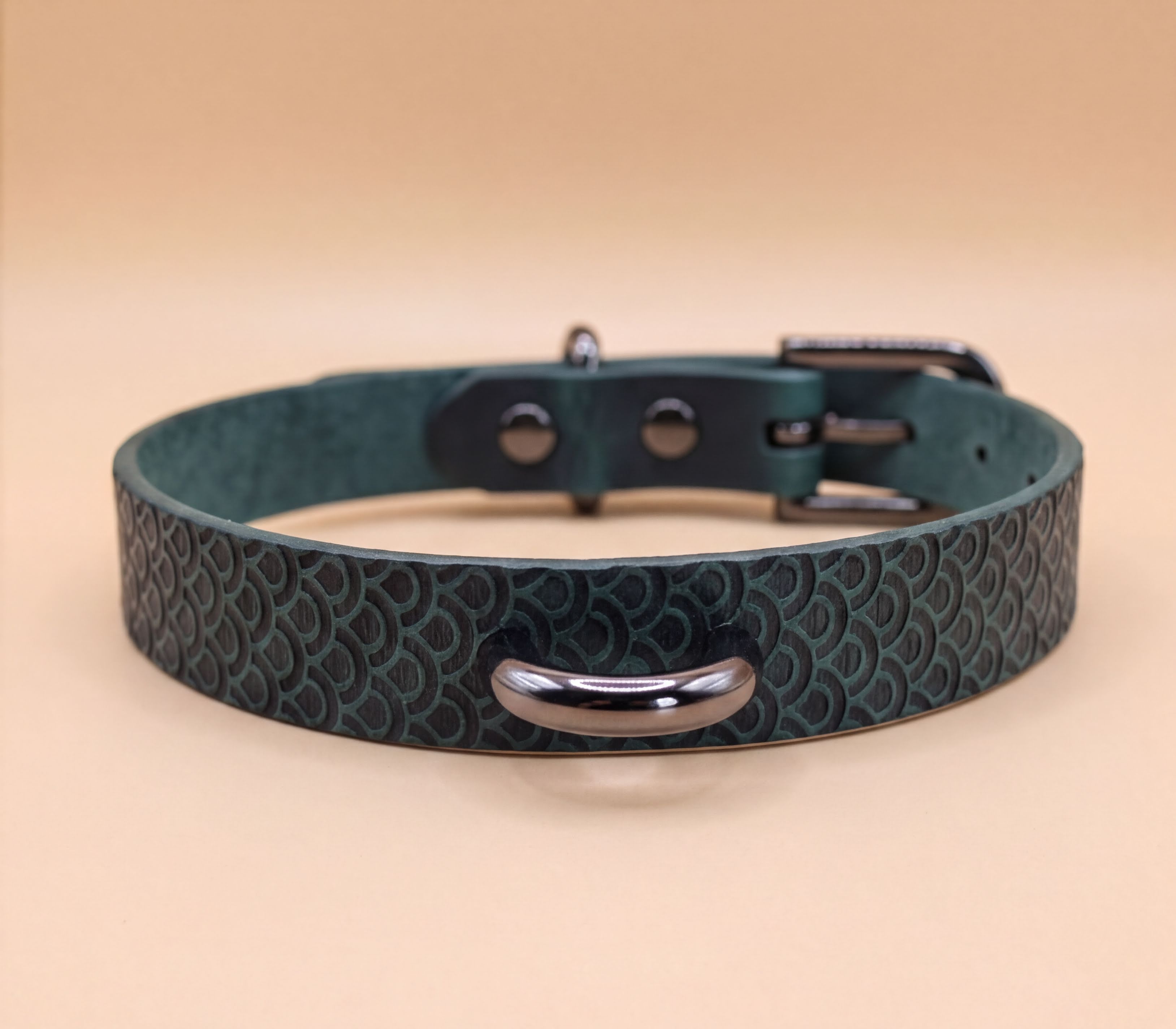 A dark green leather dog collar with a metal buckle and two metal studs on the top.