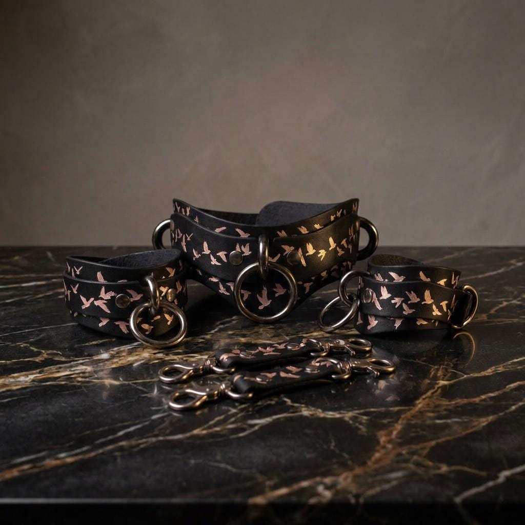 a set of black leather straps with a floral pattern, arranged on a marble surface.