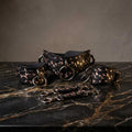 a set of black leather straps with a floral pattern, arranged on a marble surface.