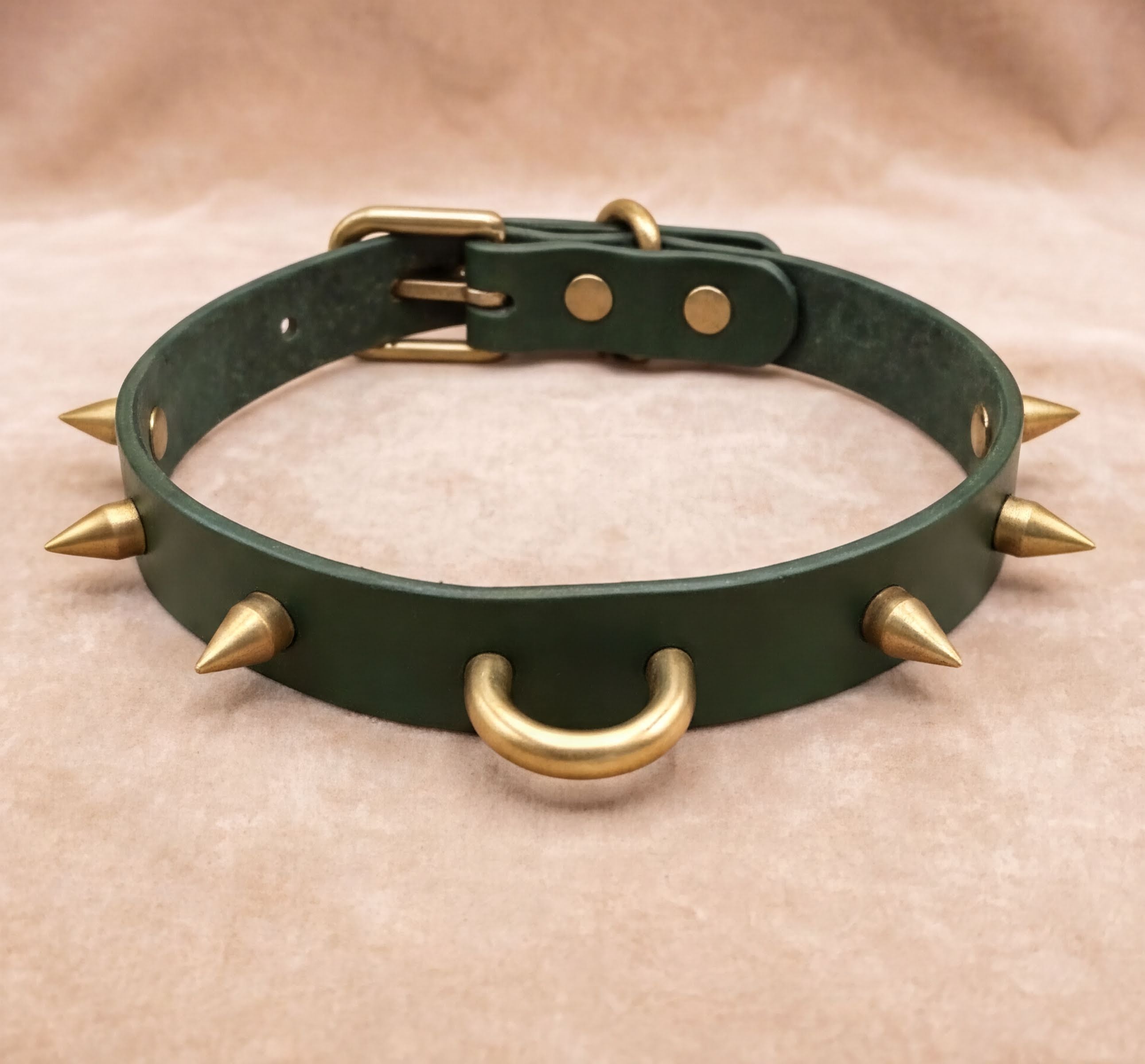A green leather dog collar with spikes protruding from it.