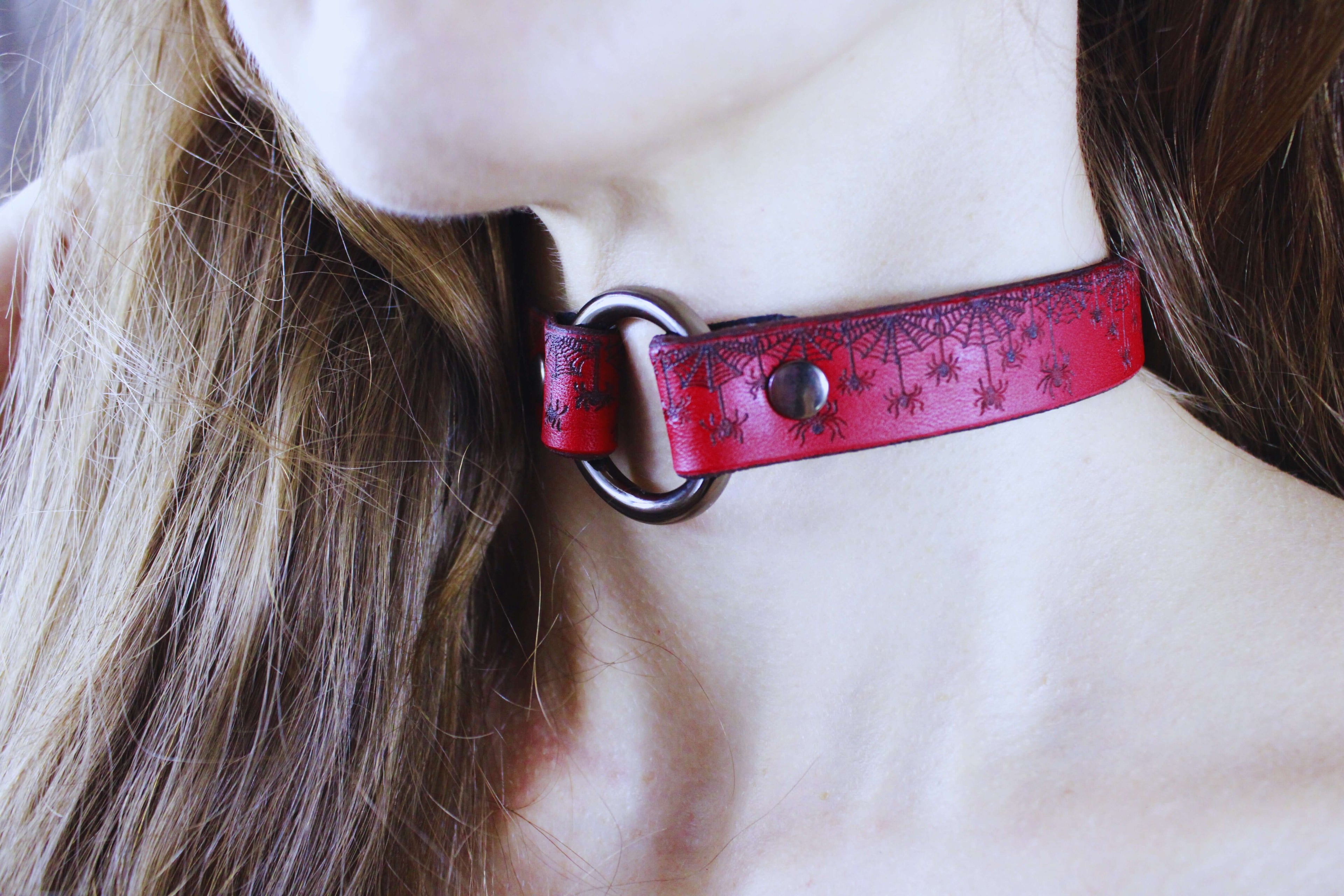 Red Spiderweb Submissive Collar worn as a gothic leather choker with spiderweb motifs.