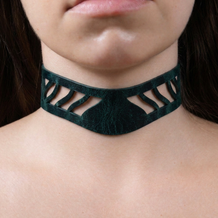A close-up of a person's neck and chest area wearing a dark green choker necklace with a unique cutout design.