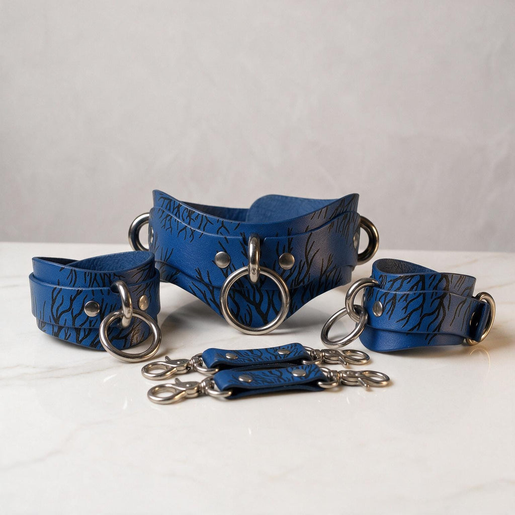 A set of blue leather choker necklaces with metal rings and buckles, arranged on a white surface.