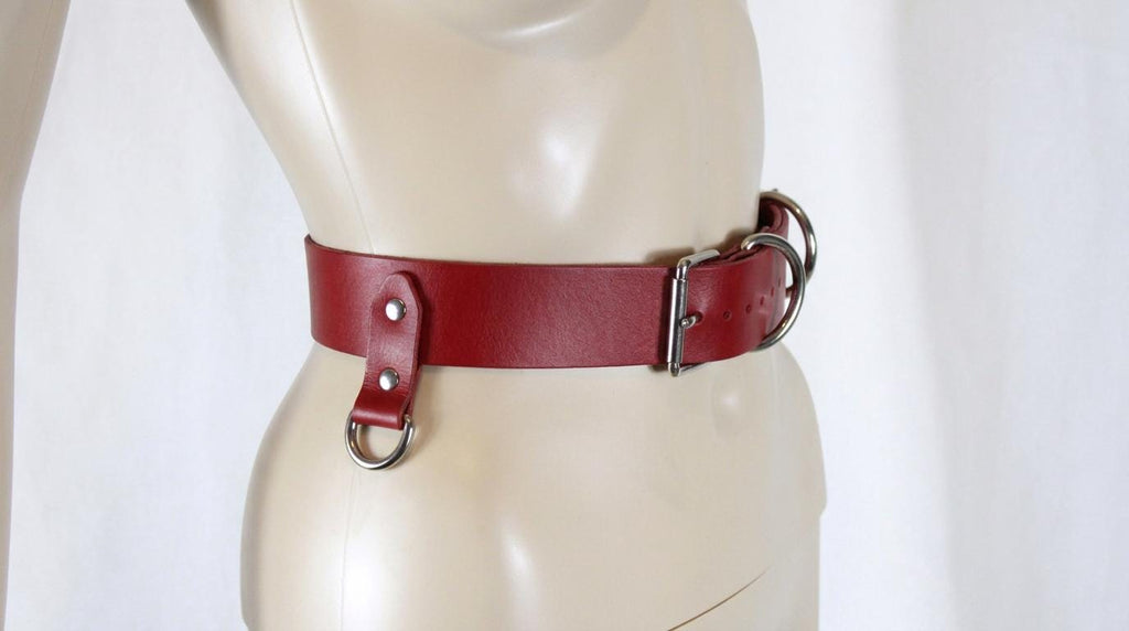 A mannequin wearing a red leather belt with metal buckles.