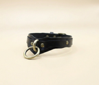 A black leather choker necklace with a metal ring and buckle.