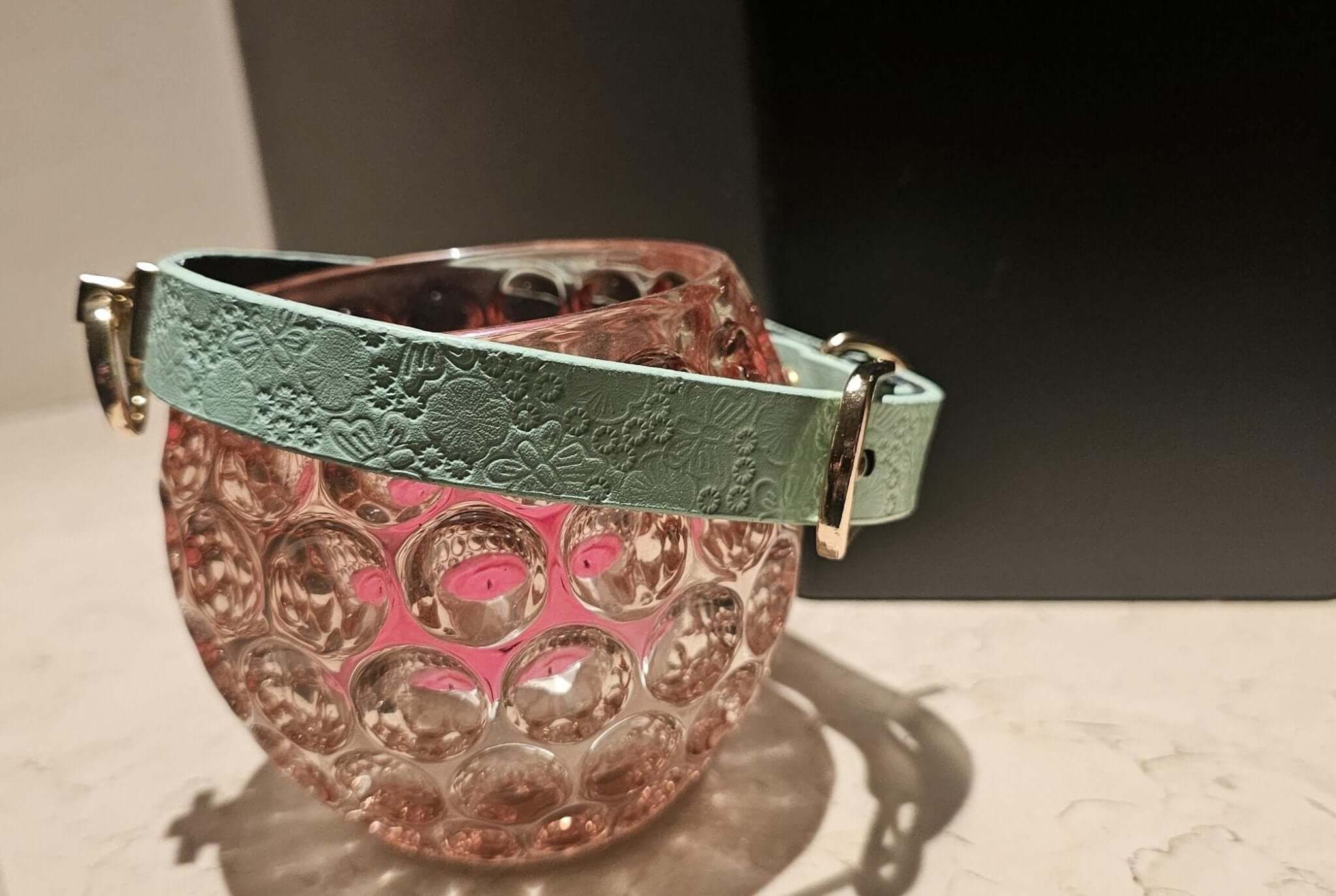 Elegant pastel mint leather collar with floral embossing displayed on a decorative glass vase.