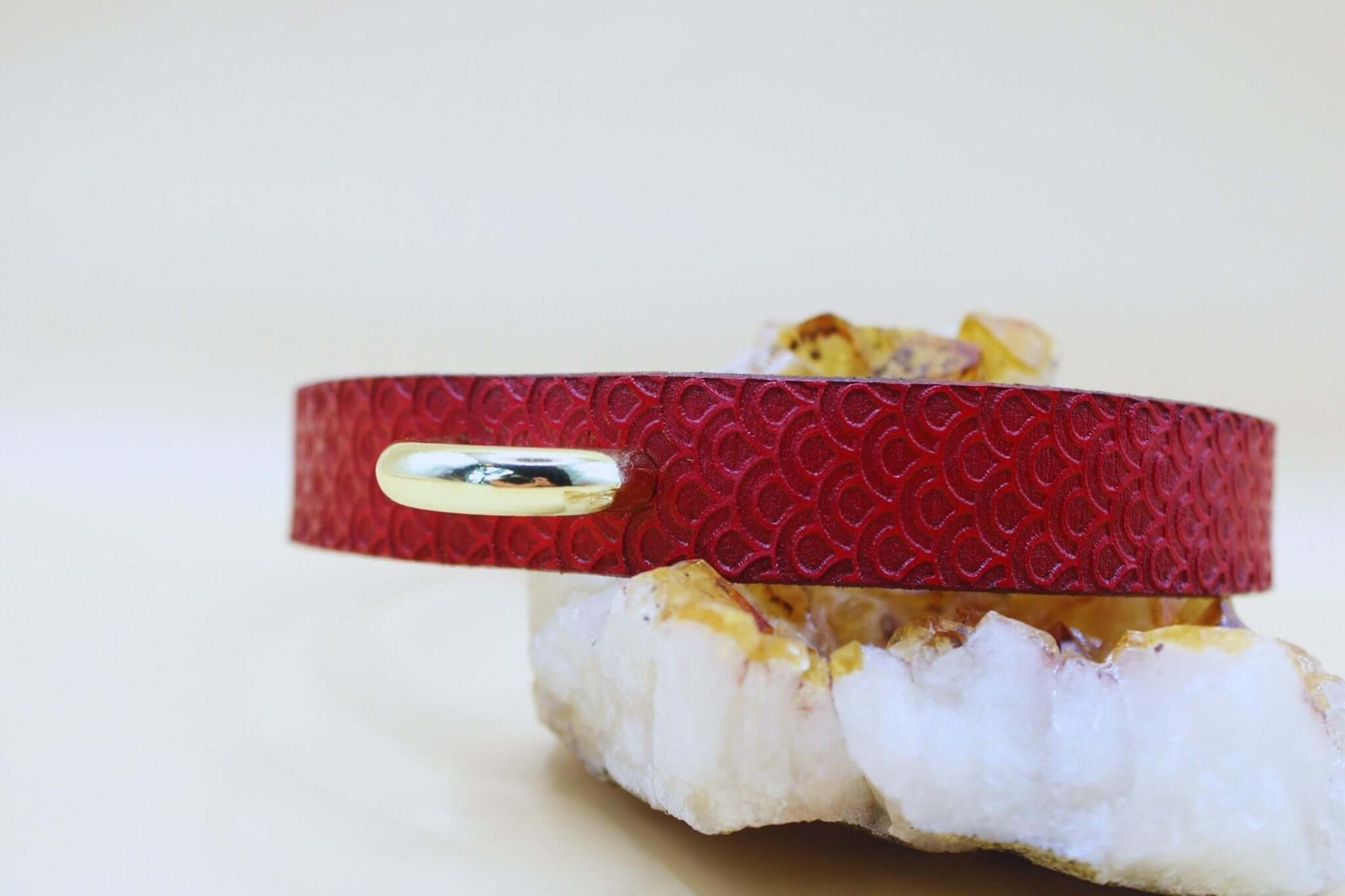 Elegant red leather BDSM collar on a mineral rock, perfect for submissive jewelry and decor in dom/sub relationships.