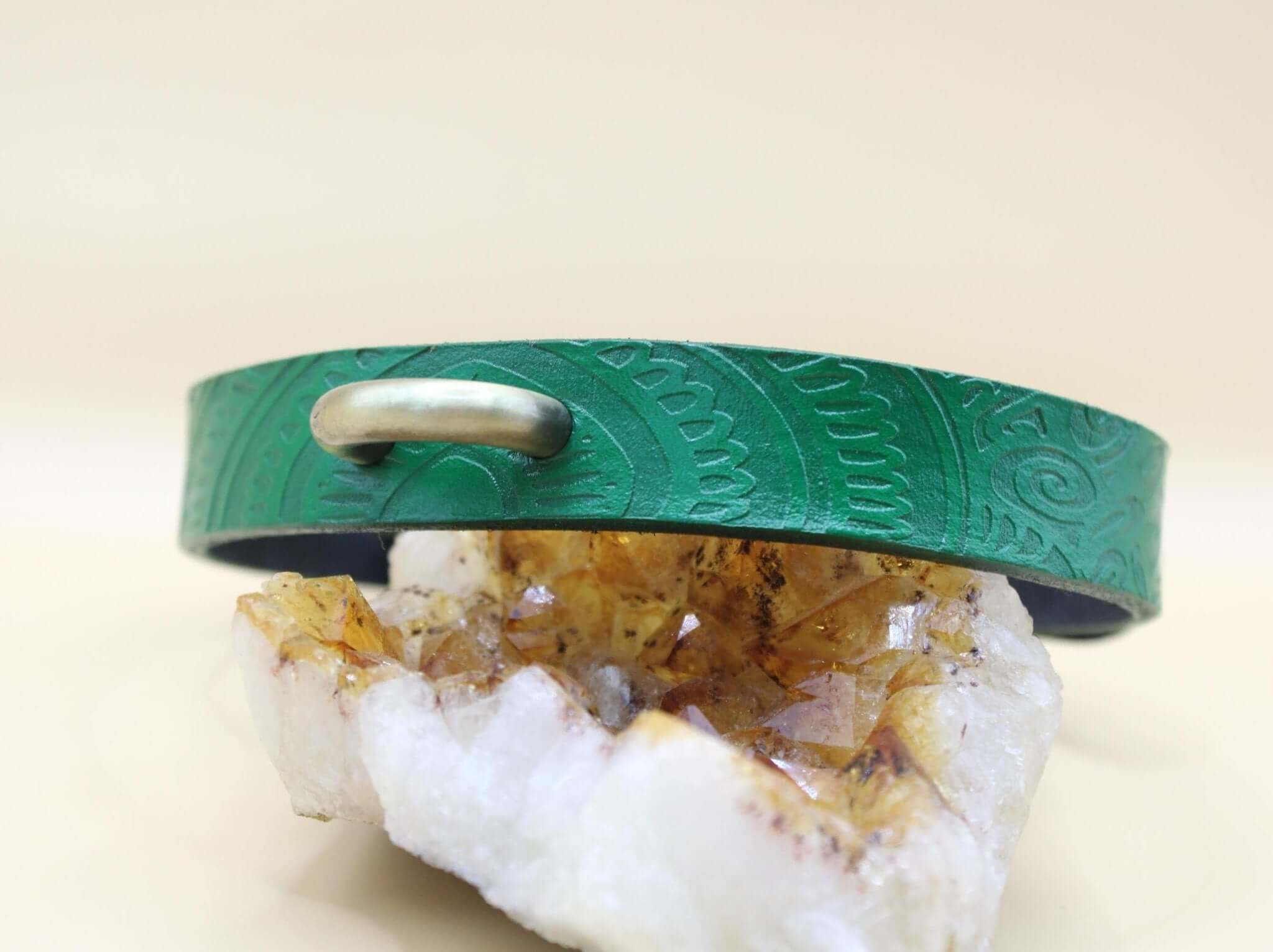 Emerald green handcrafted leather submissive collar displayed on crystal, perfect for BDSM and dom/sub style.