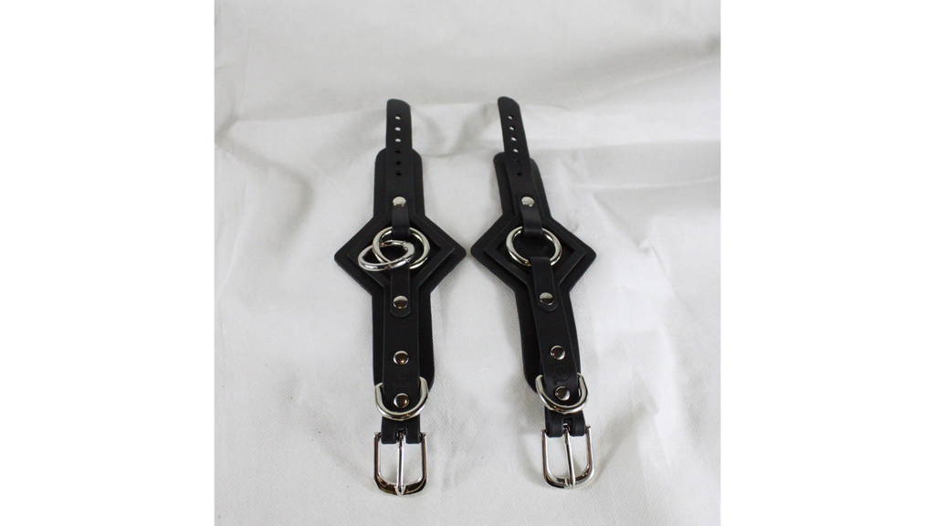 a pair of black leather straps with metal rings and buckles, placed side by side on a white background.