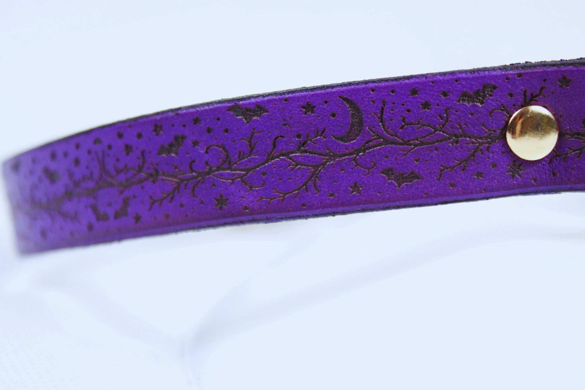 A purple leather strap with a decorative pattern of stars, bats, and a crescent moon.