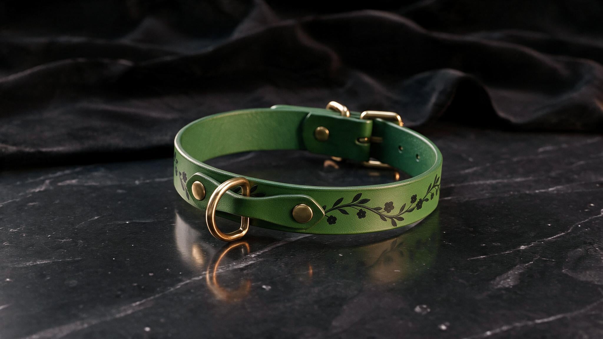 A green leather collar with a leaf design sits on a black marble surface.