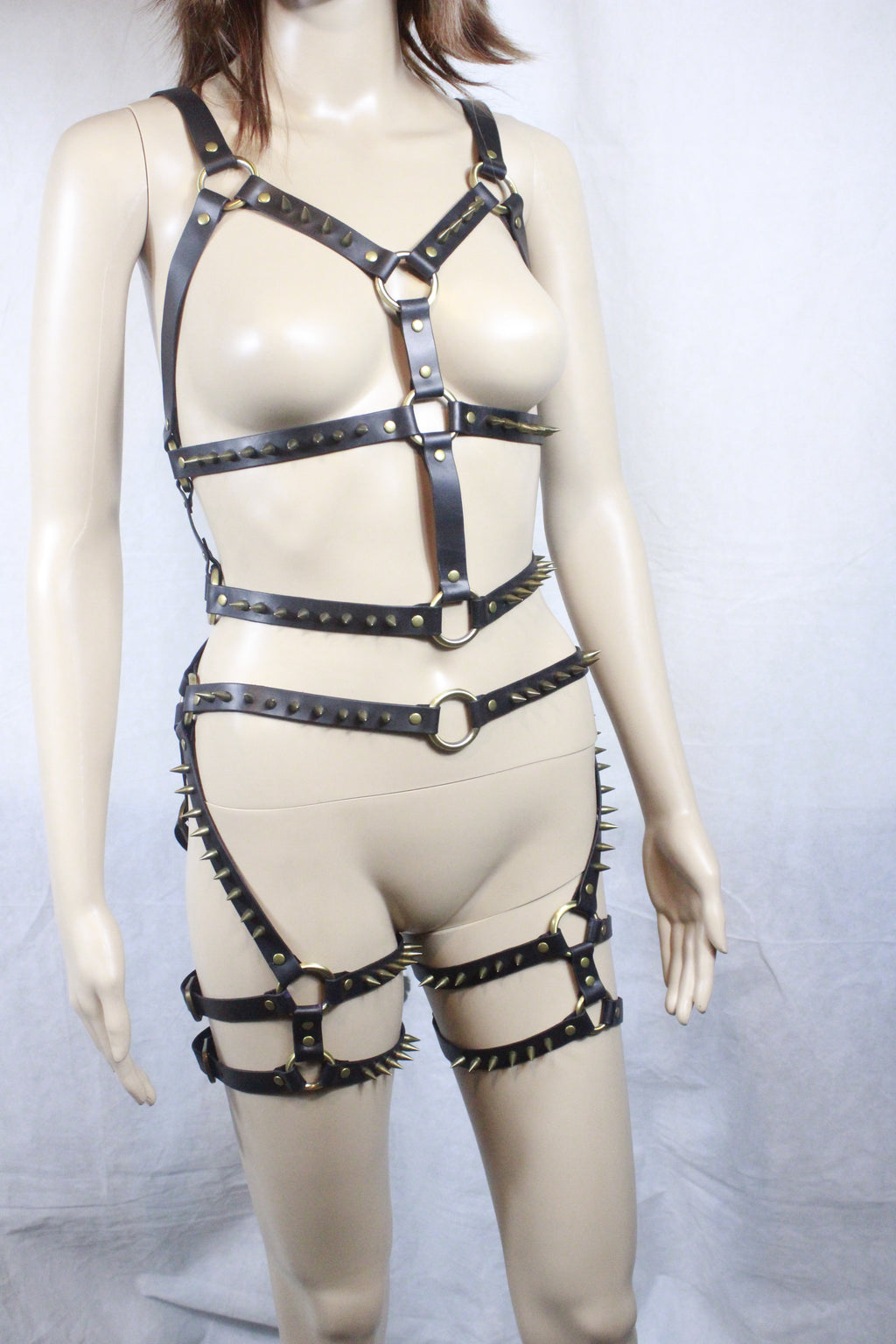 A mannequin wearing a leather strap ensemble with spikes on the straps.