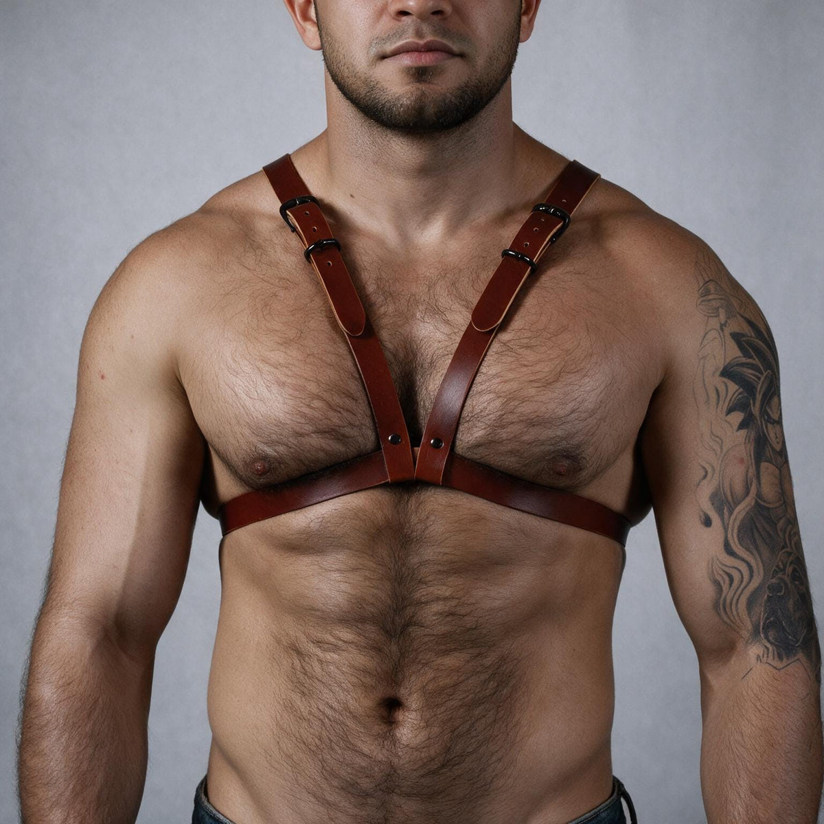 A shirtless man wearing a leather harness with straps across his chest.