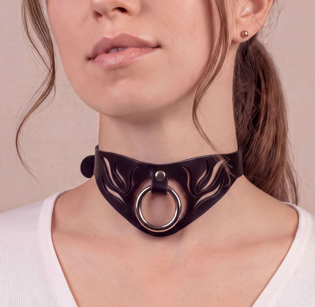 A close-up of a woman's face wearing a black choker necklace with a circular metal ring.